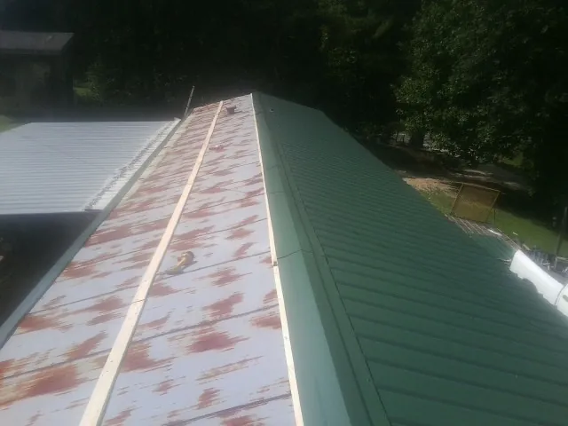 Old rusted panels beside newly installed green metal roofing — Wind Damage Roof Repair by Roofing Brothers in Platteville