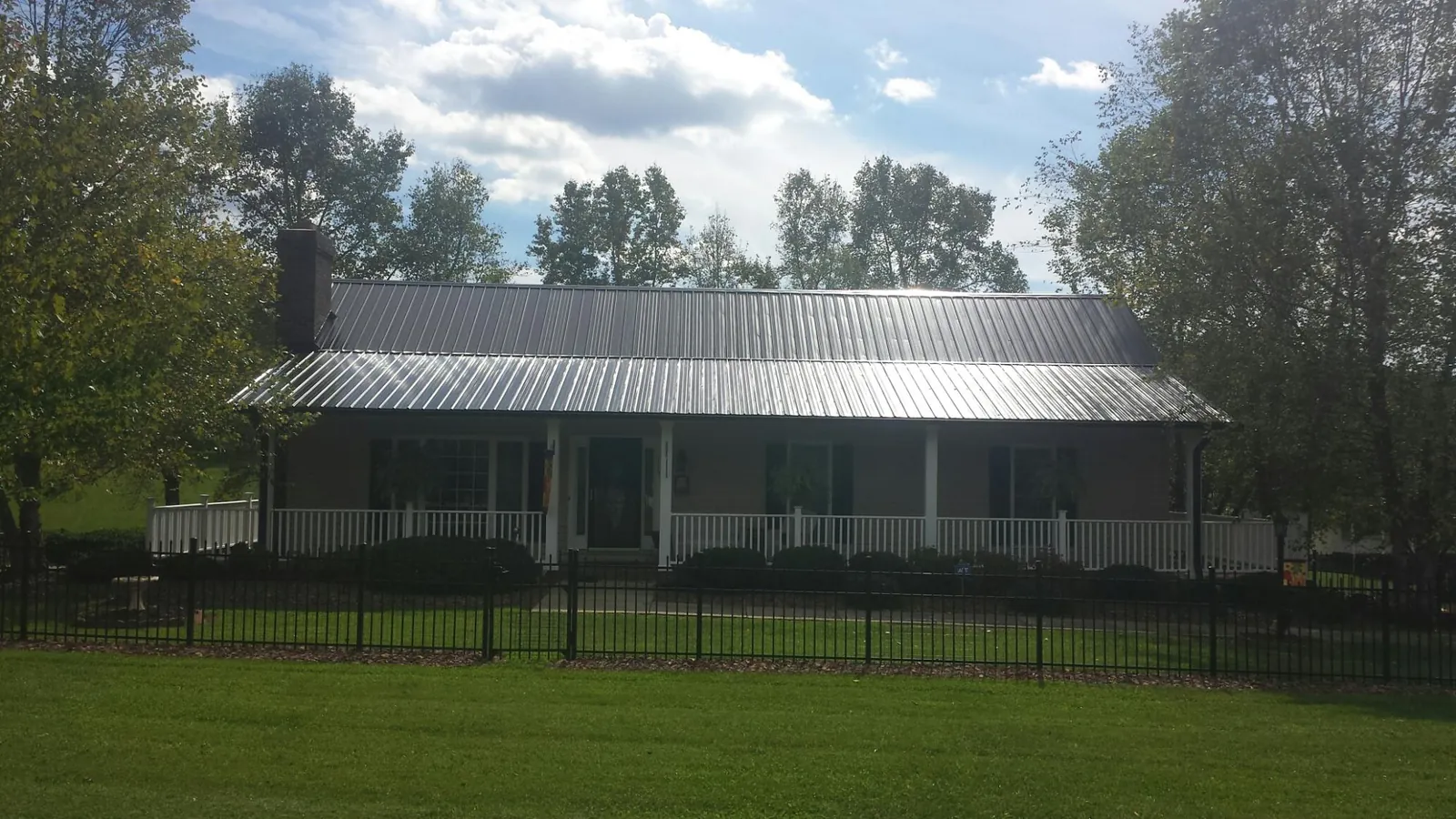 Gray metal roof on a brick ranch with a full width front porch — Gutter Guard Installation work by our crew in Platteville