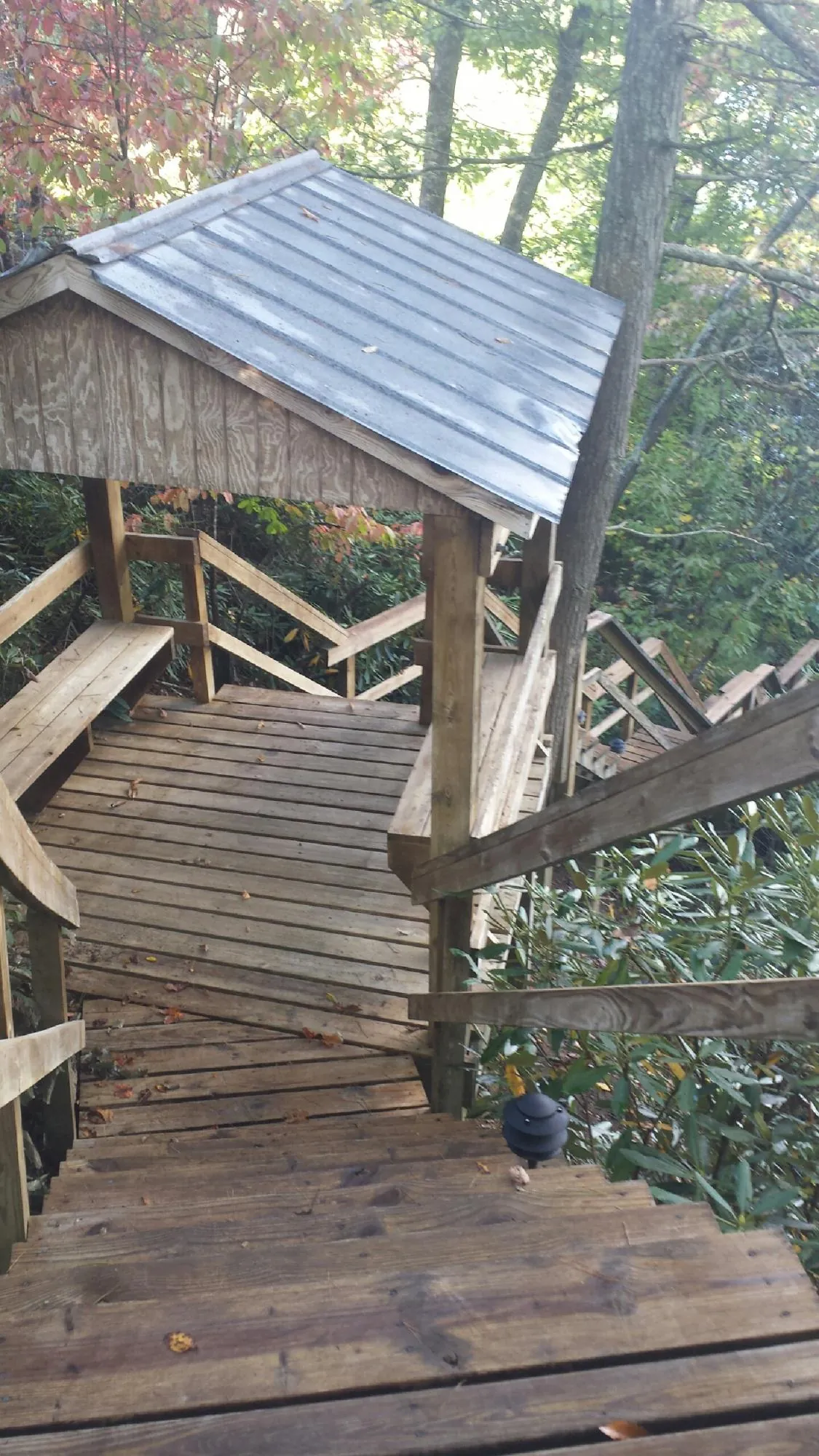 Metal roofed shelter over wooden steps on a wooded walkway — Skylight Repair & Installation work by our crew in Platteville